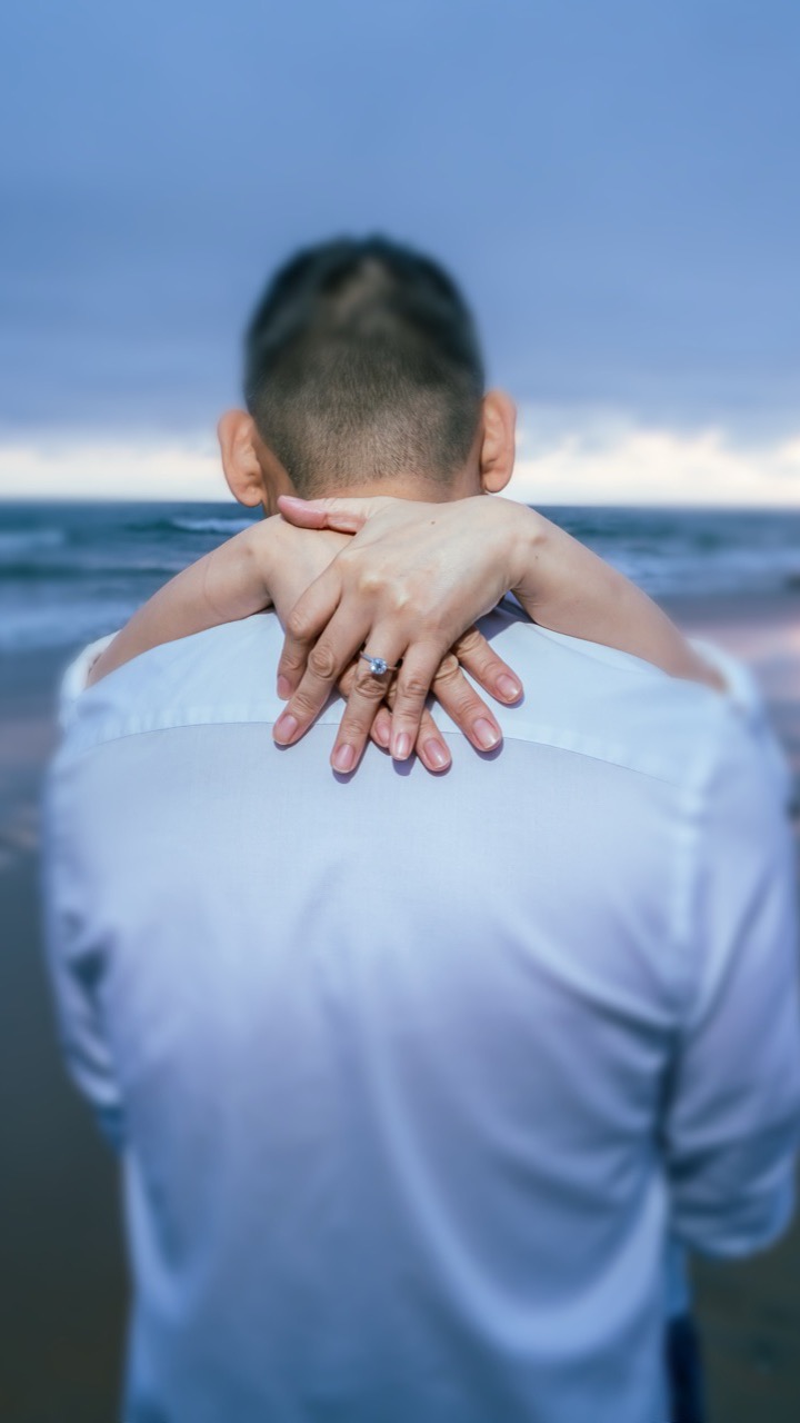 Rhona's hands resting on Francis's shoulders, engagement ring in view
